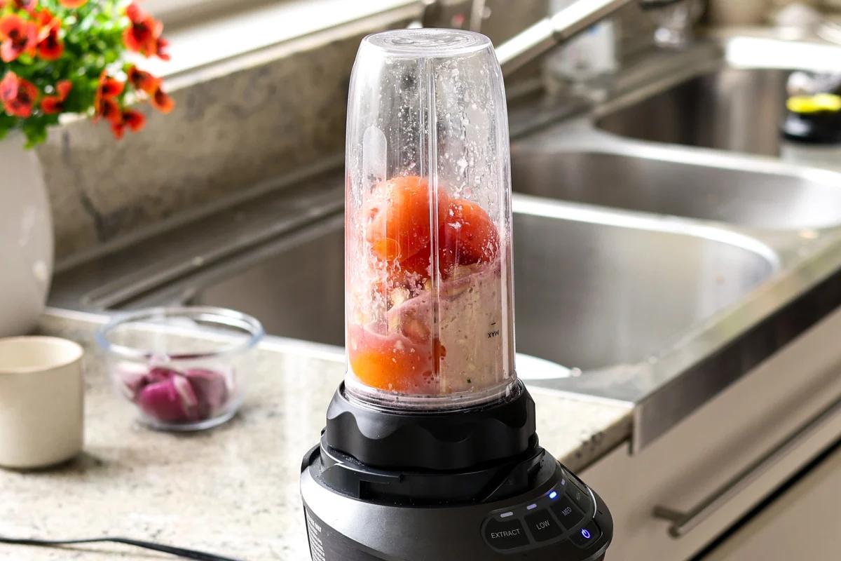 adding tomatoes, cashews, and spices to the blender