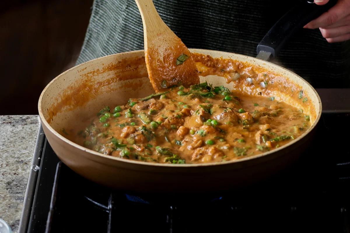 mixing peas into the sauce
