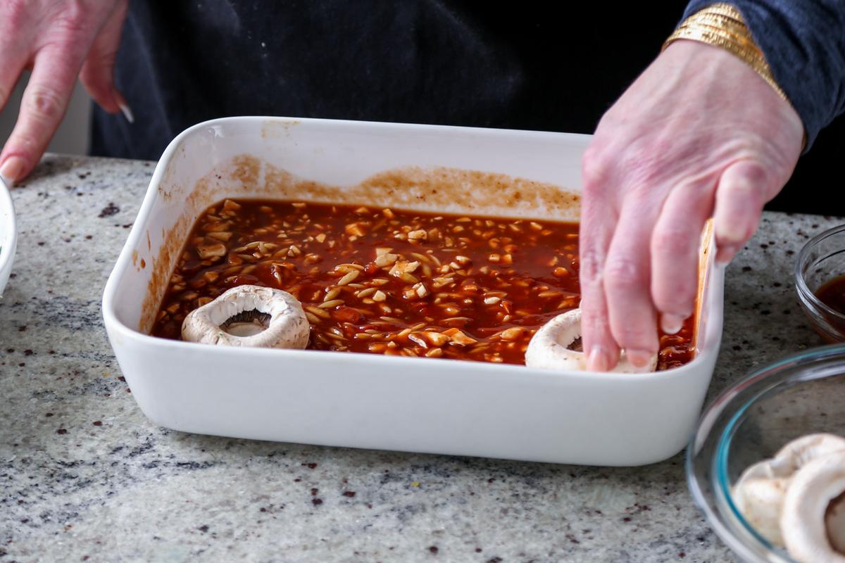 adding mushrooms to the pan of pasta