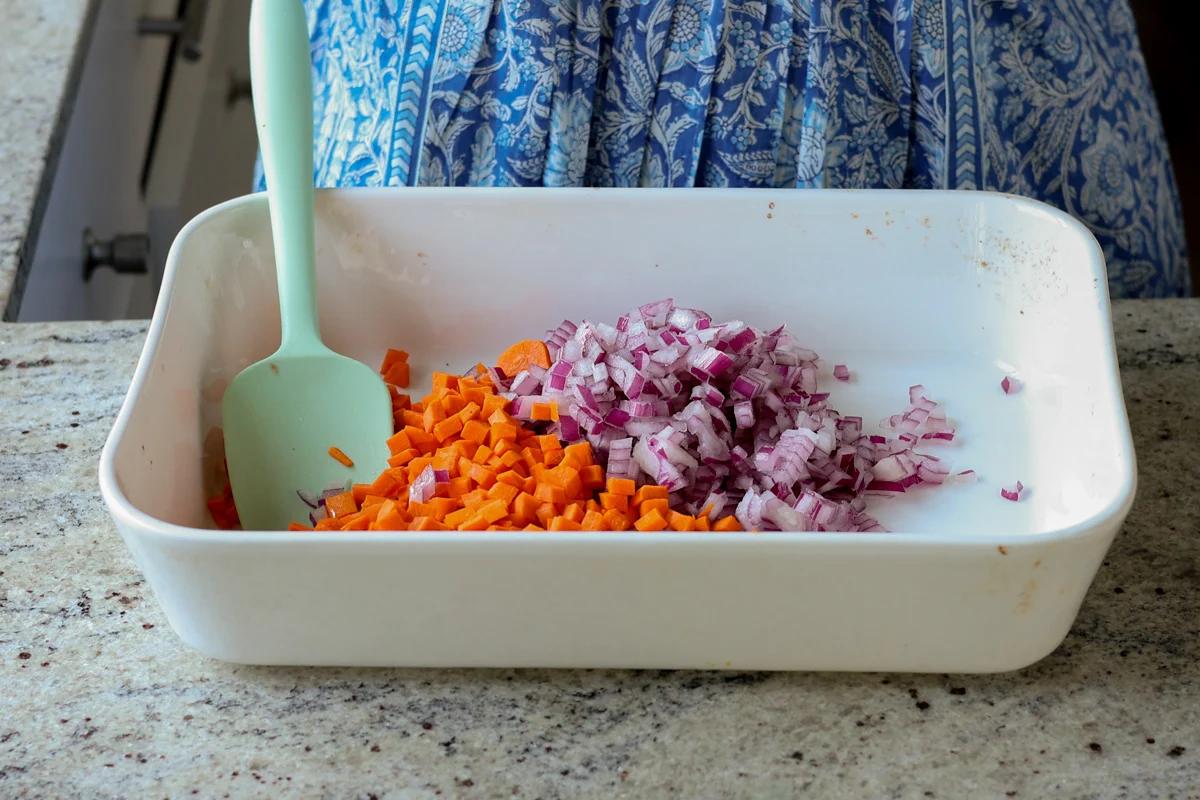 adding carrots and onion to the baking pan