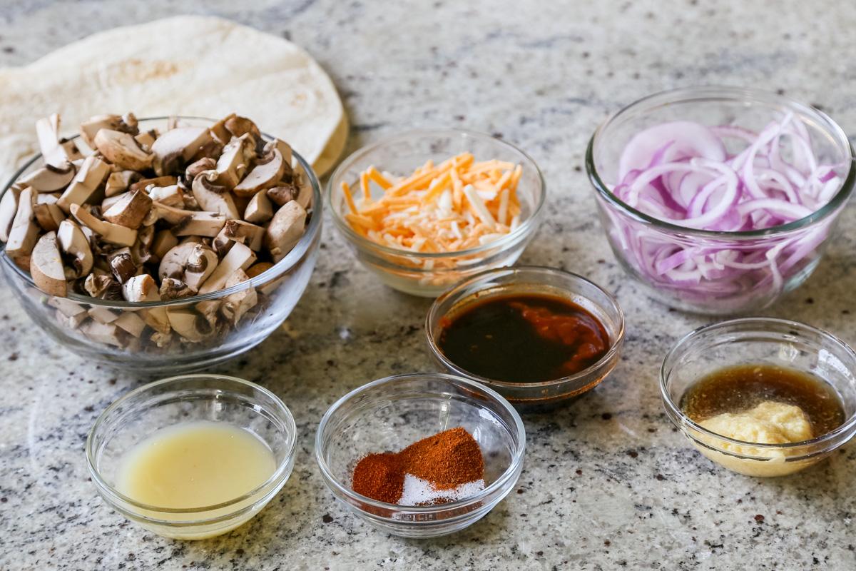 mushrooms, vegan cheese, and other quesataco ingredients in bowls on a white table