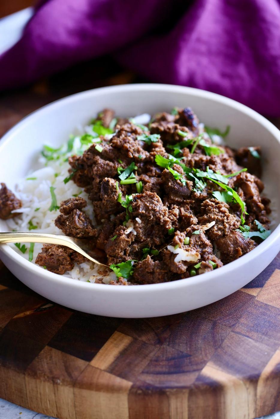a serving of vegan mushroom xacuti served with rice sprinkled with cilantro