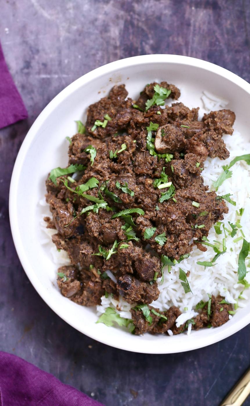 a serving of vegan mushroom xacuti with rice in a white bowl