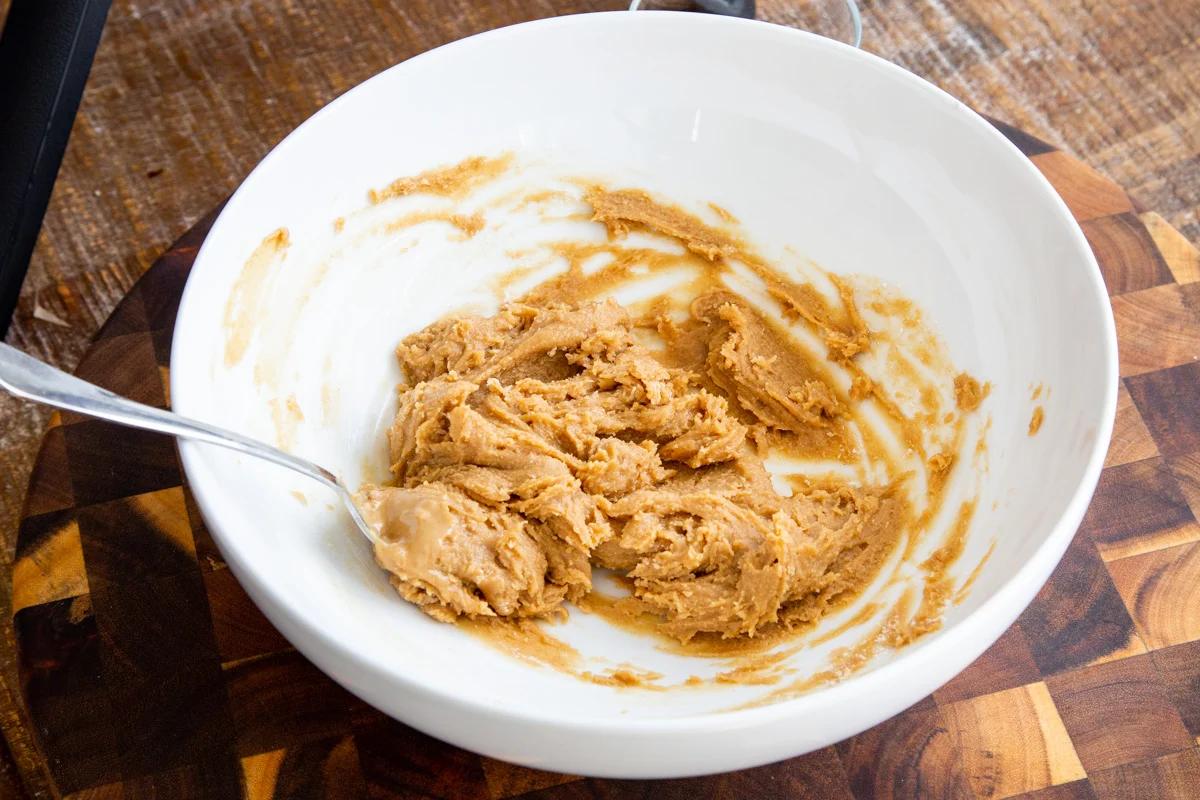 peanut butter and almond flour being stirred together in a white bowl