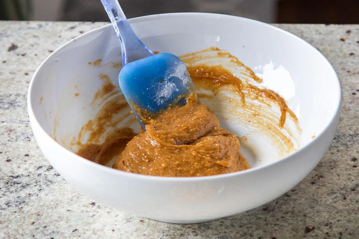 smooth peanut butter being mixed with maple syrup and baking soda