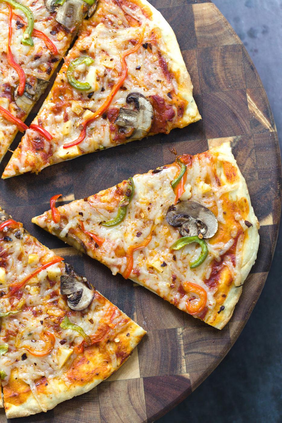 overhead shot of a freshly baked vegan pizza cut into wedges