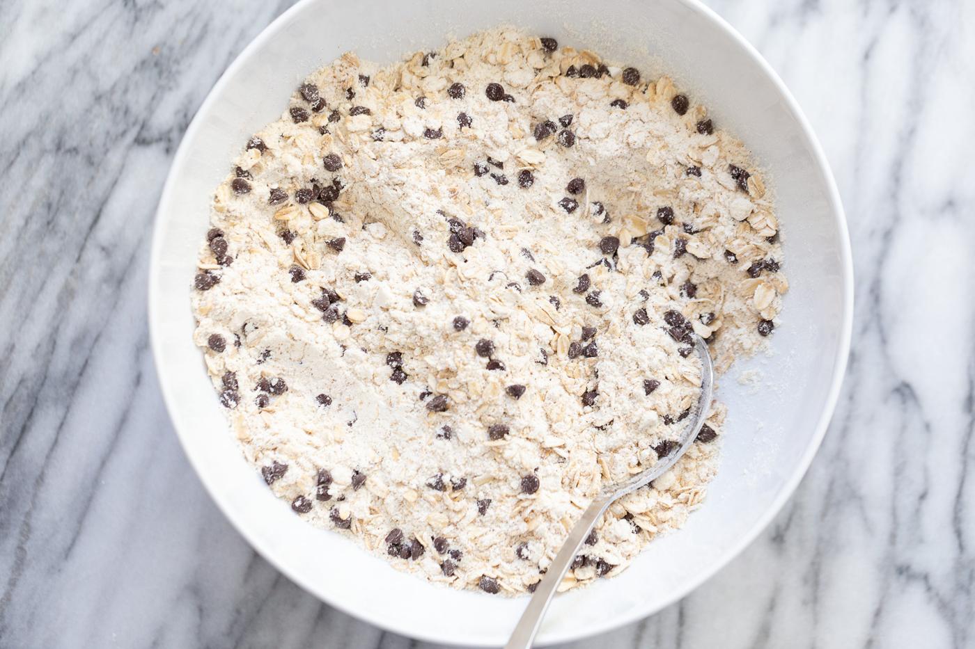 dry ingredients for vegan oatmeal chocolate chip waffles being stirred in a white bowl