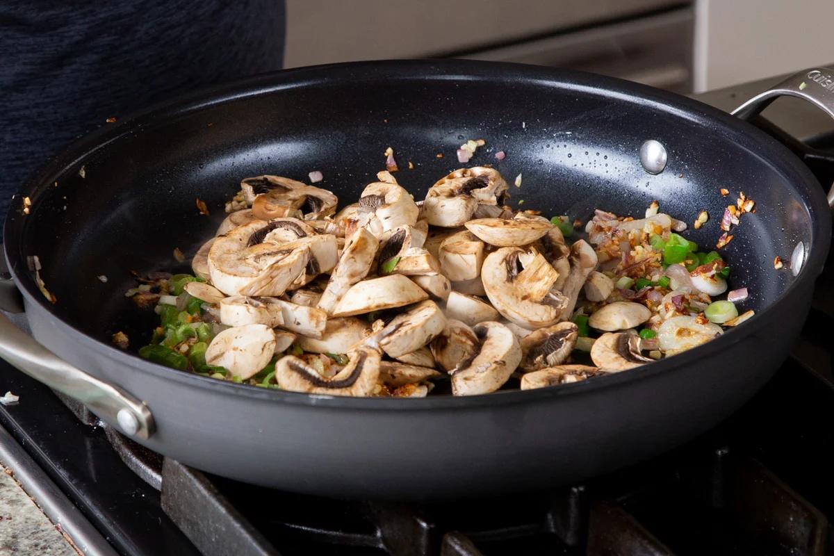 adding mushrooms to the frying pan