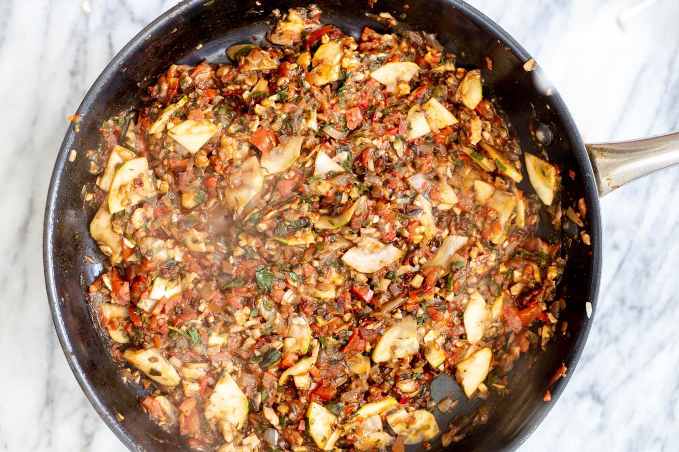 veggies stir-frying in a black sauteeing pan