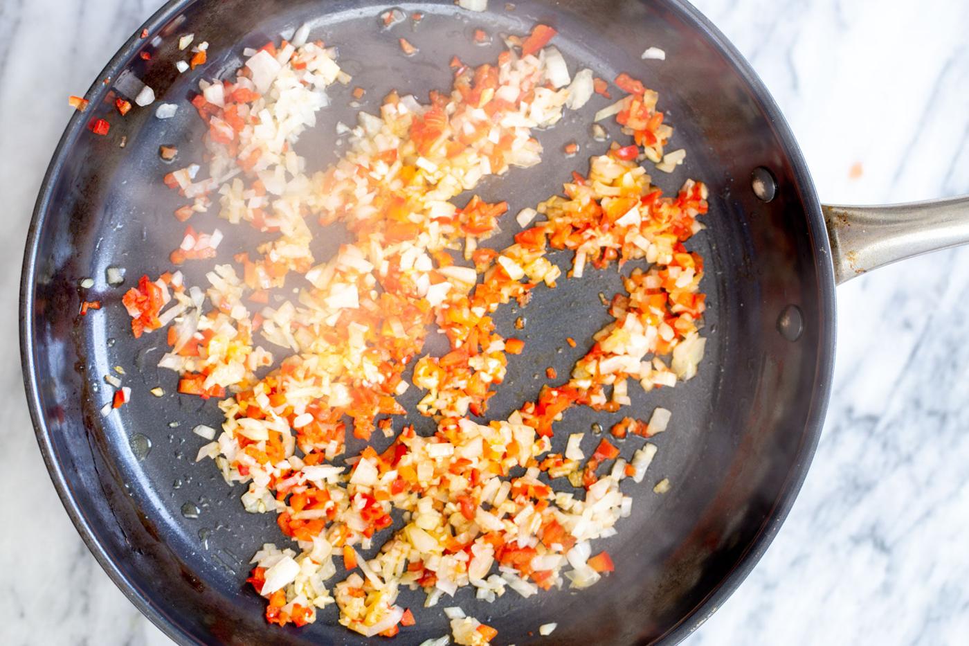 red chili flaked garlic and onion in a sauteeing pan