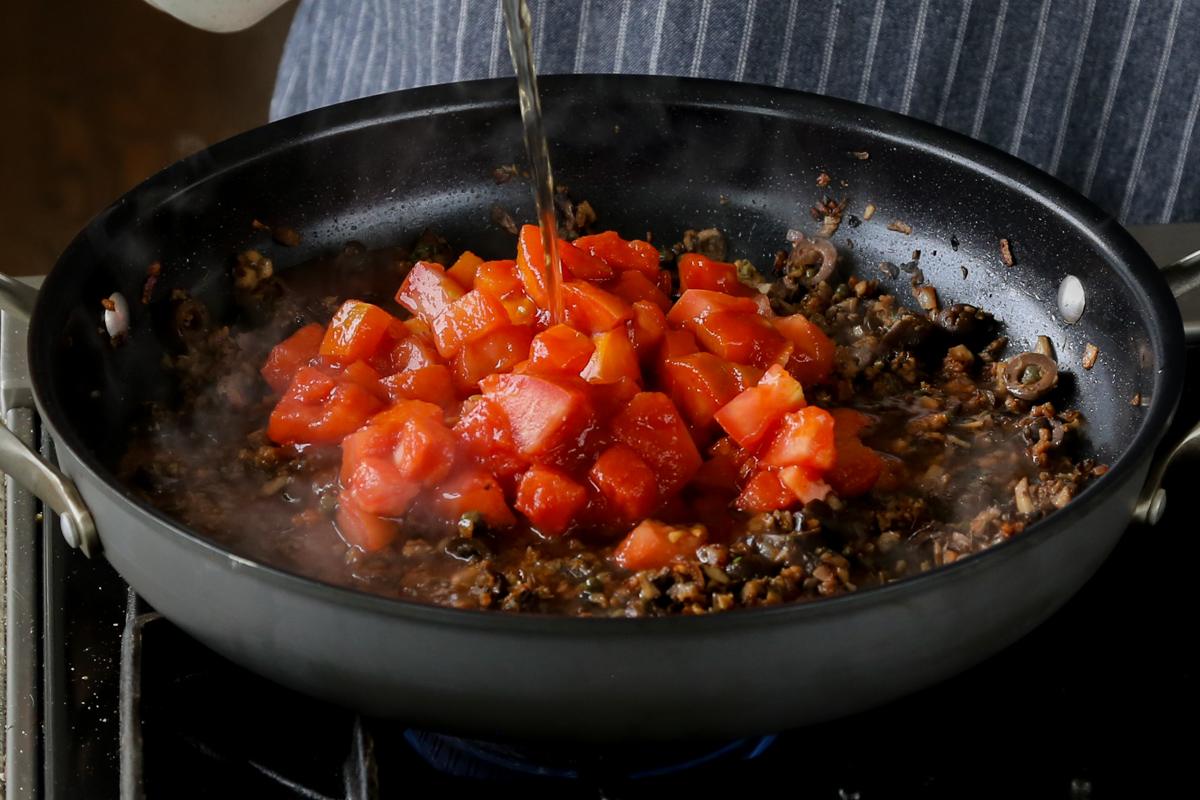 adding tomatoes and stock to the pan