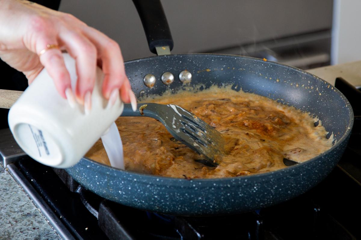 adding non-dairy milk to the yogurt-onion mixture in the pan