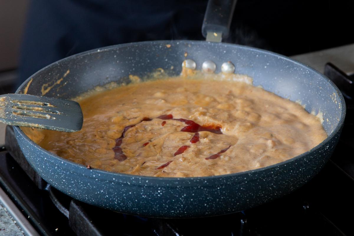 adding tomato paste to the sauce