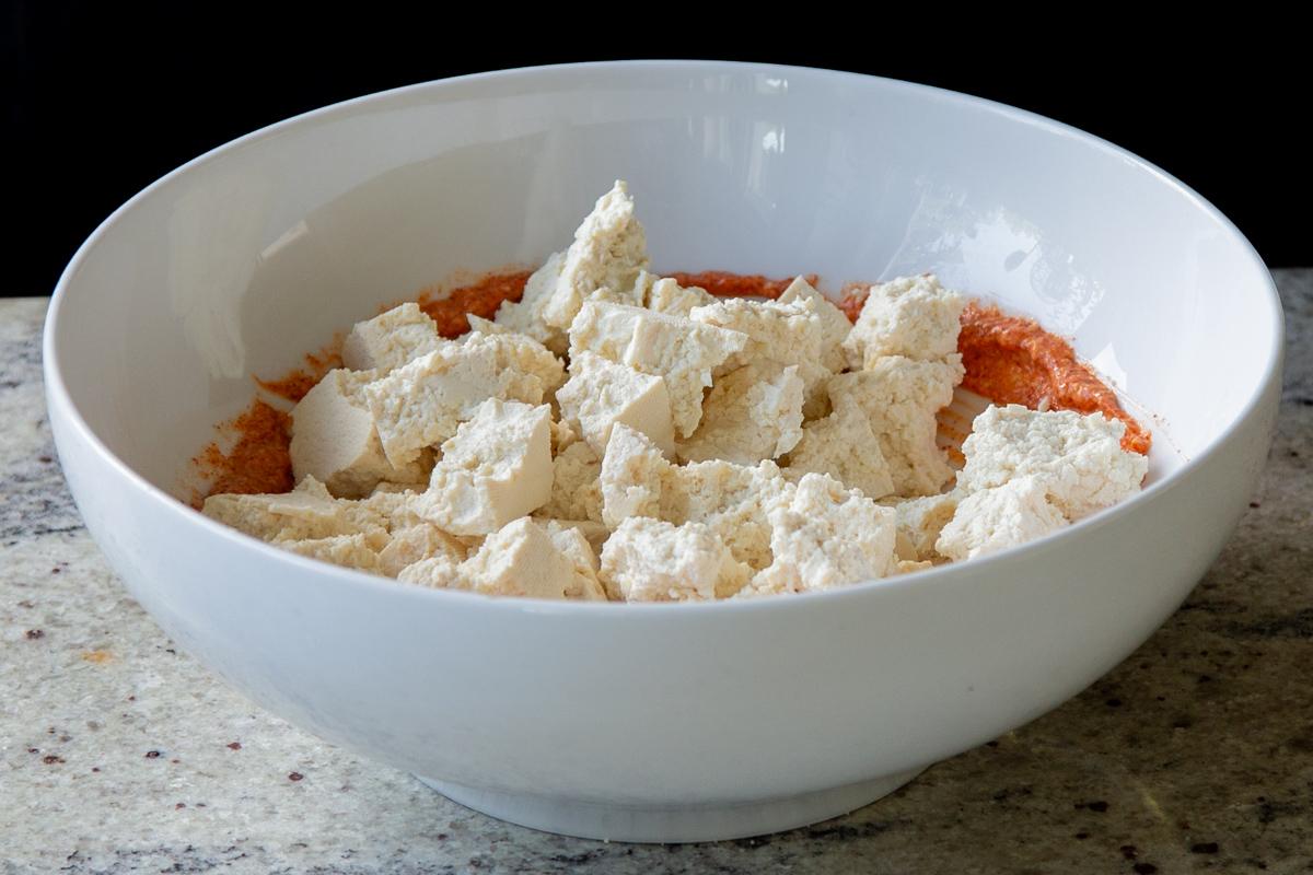 adding tofu to the bowl with the seasoned yogurt mixture