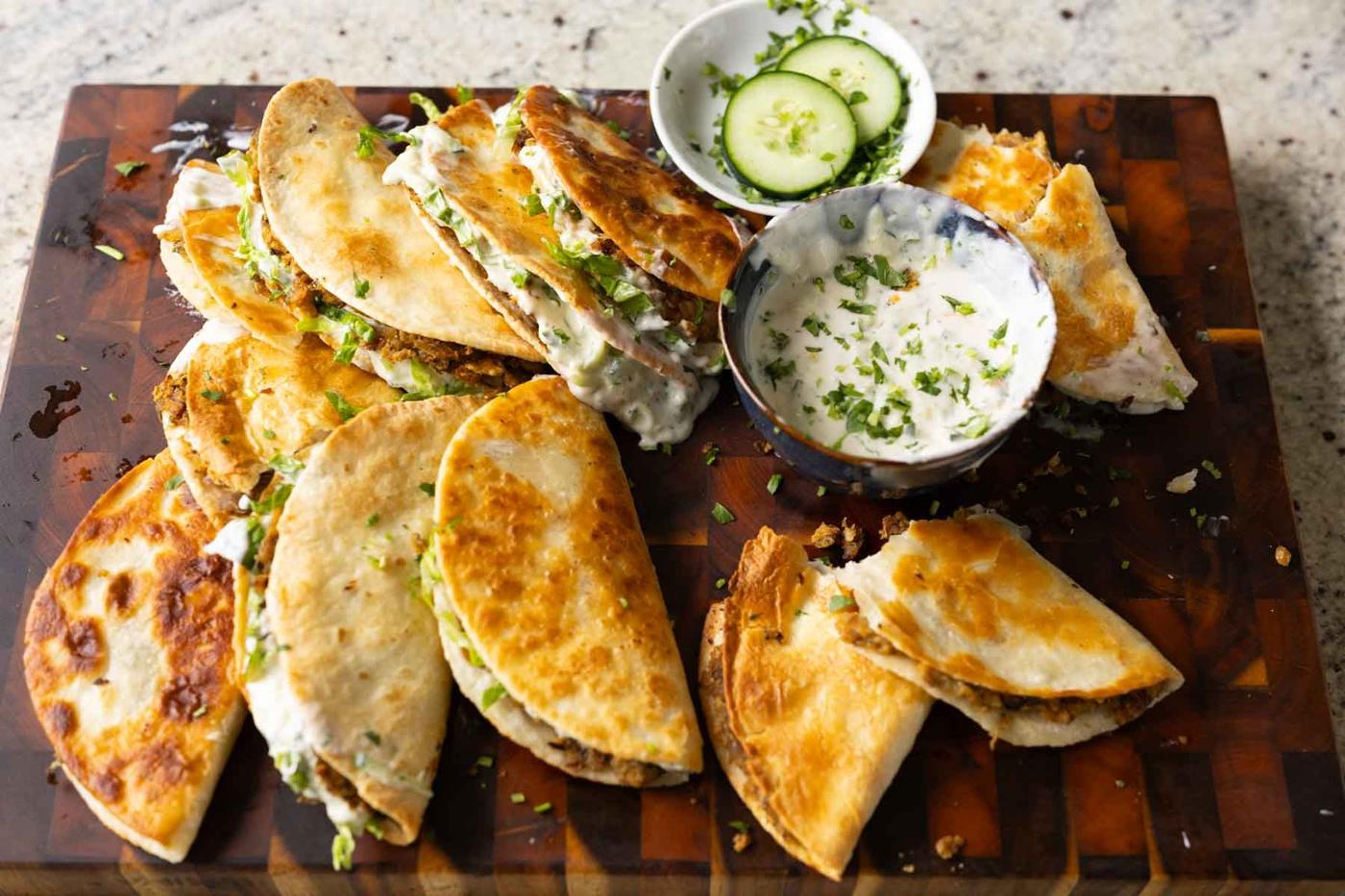 stuffed paratha tacos on a serving platter with extra raita