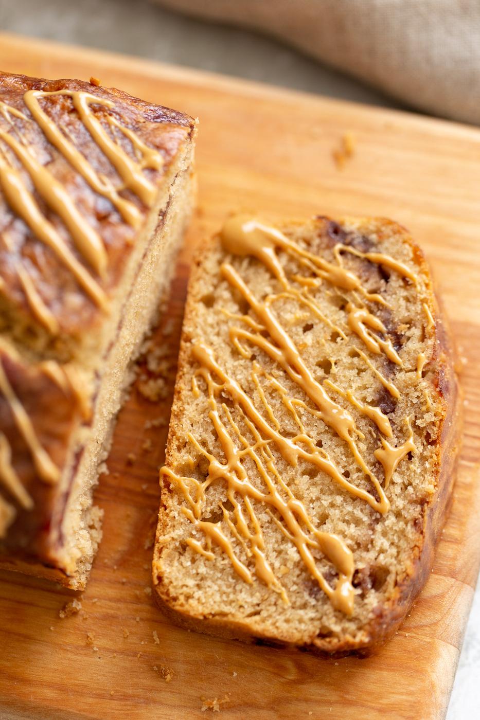 a slice of vegan peanut butter and jelly loaf cake drizzled with peanut butter