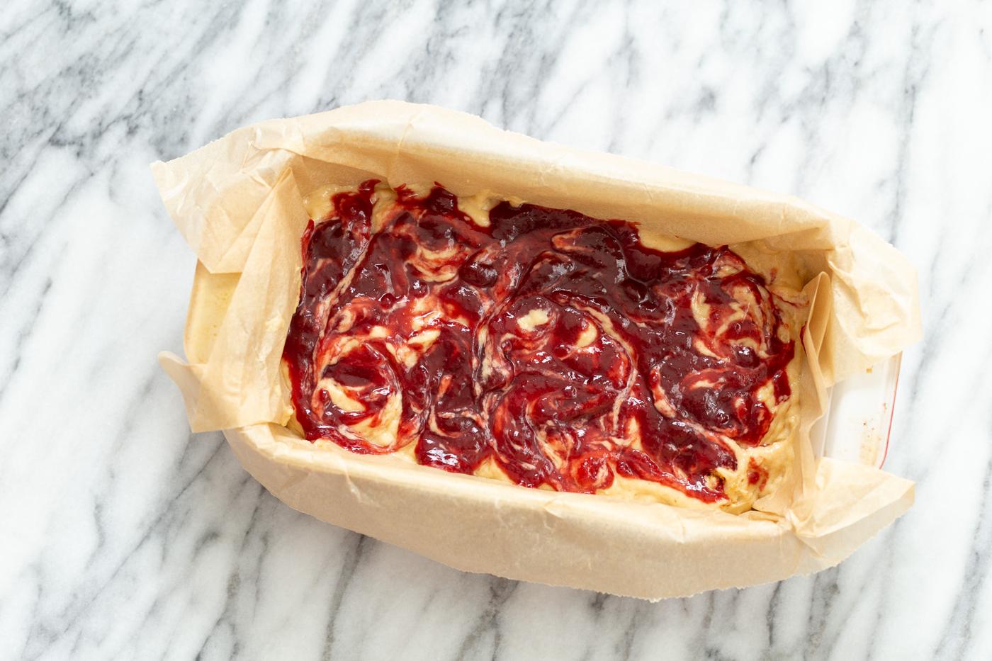 raspberry jam being swirled into peanut butter cake batter