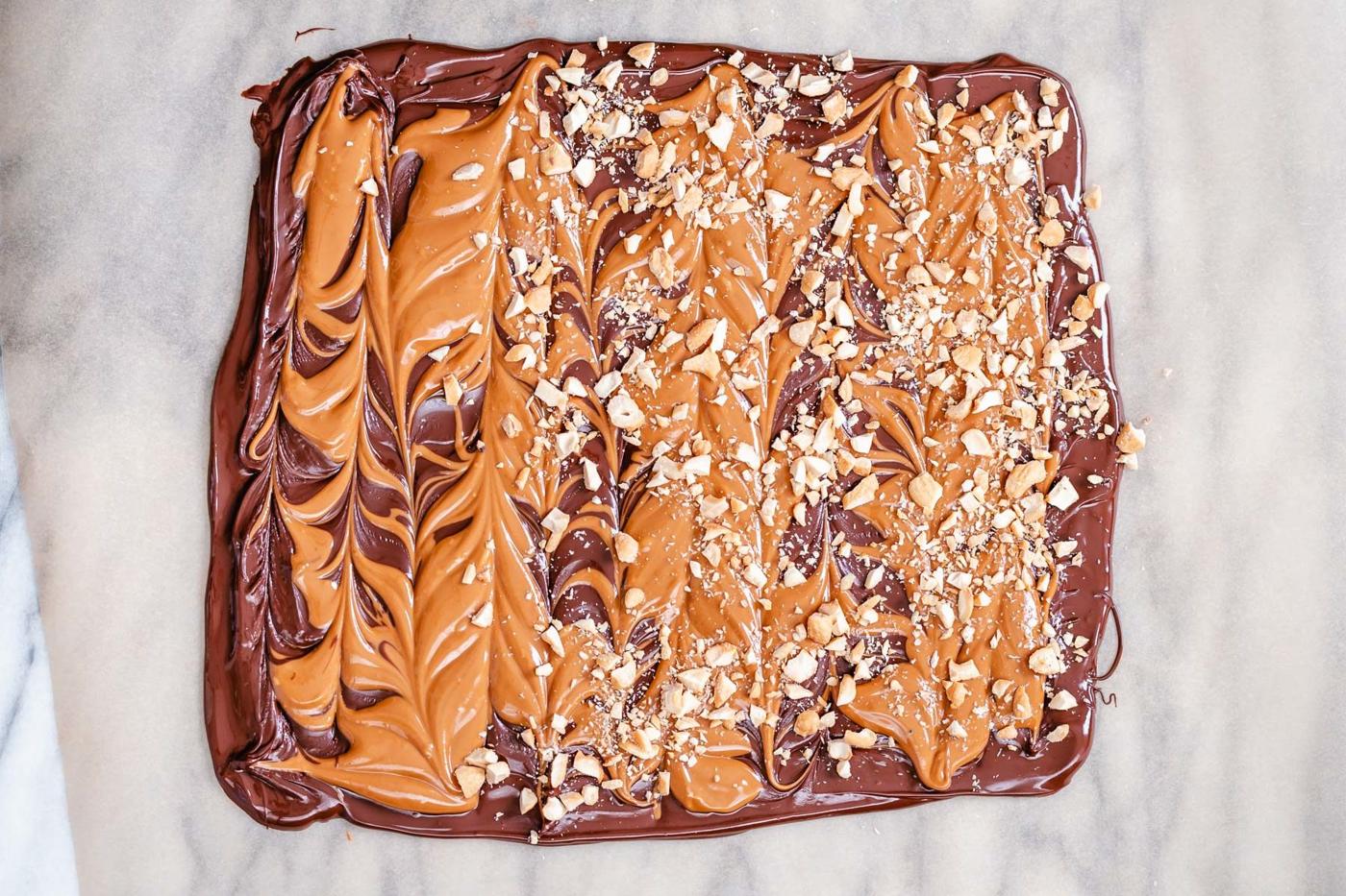 chopped peanuts being sprinkled on top of vegan peanut butter chocolate bark