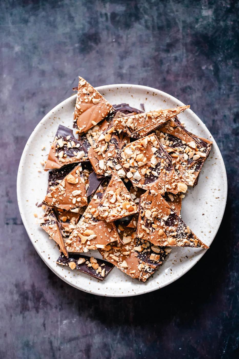 vegan dark chocolate and peanut butter bark with chopped peanuts on a white plate