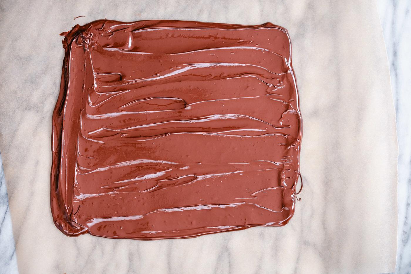 melted chocolate being spread out into a rectangle to make chocolate bark
