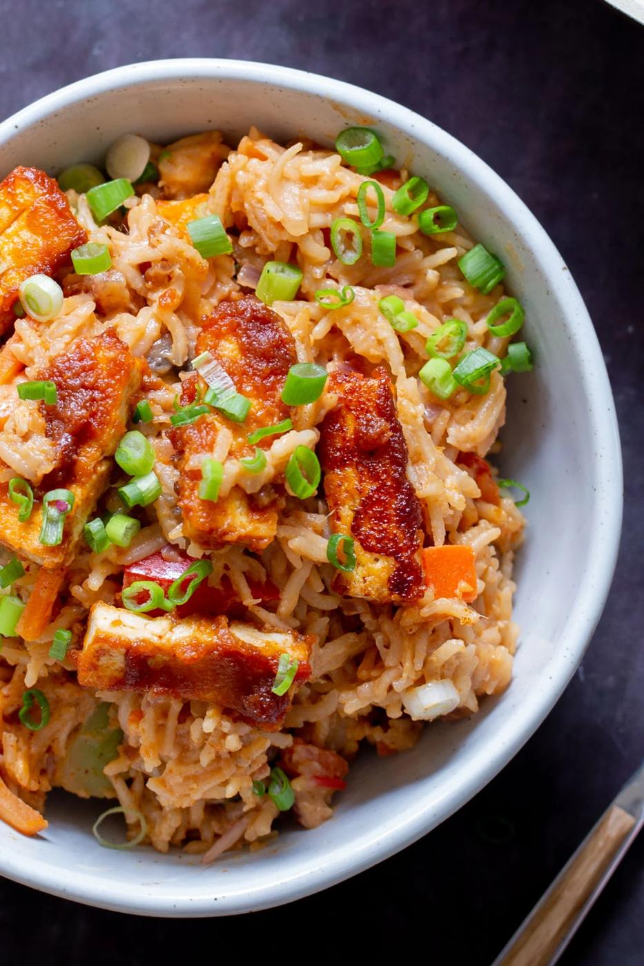 close-up of peanut gochujang rice topped with tofu and green onions in a bowl