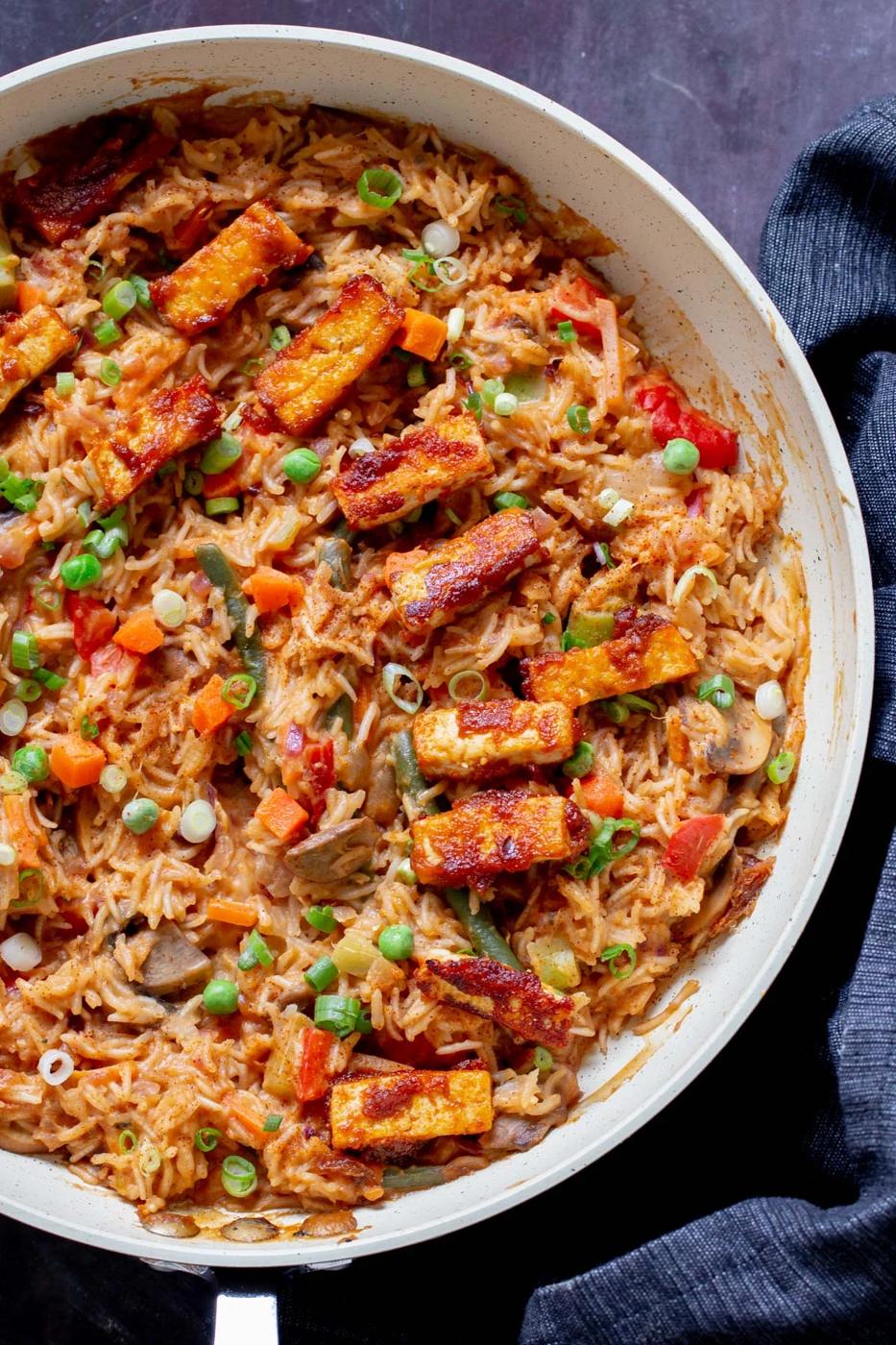 close-up of peanut gochujang rice topped with tofu and green onions in a skillet