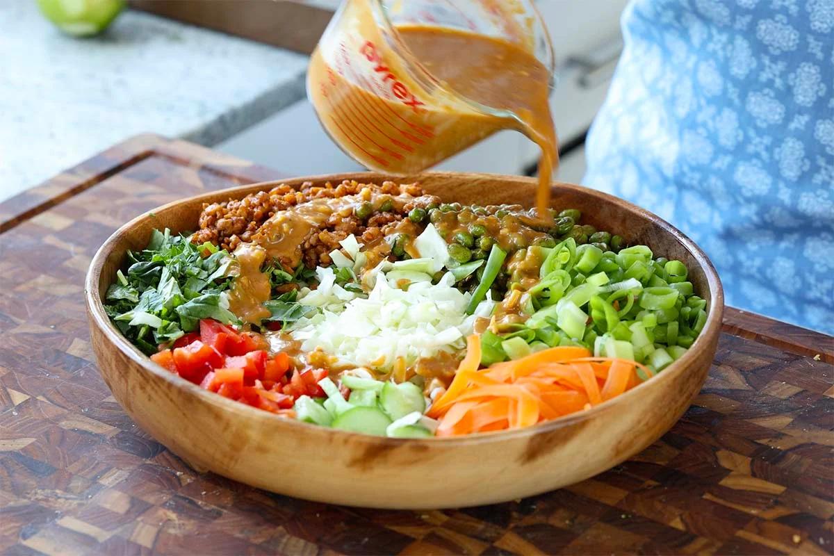 adding the dressing to the gochujang salad