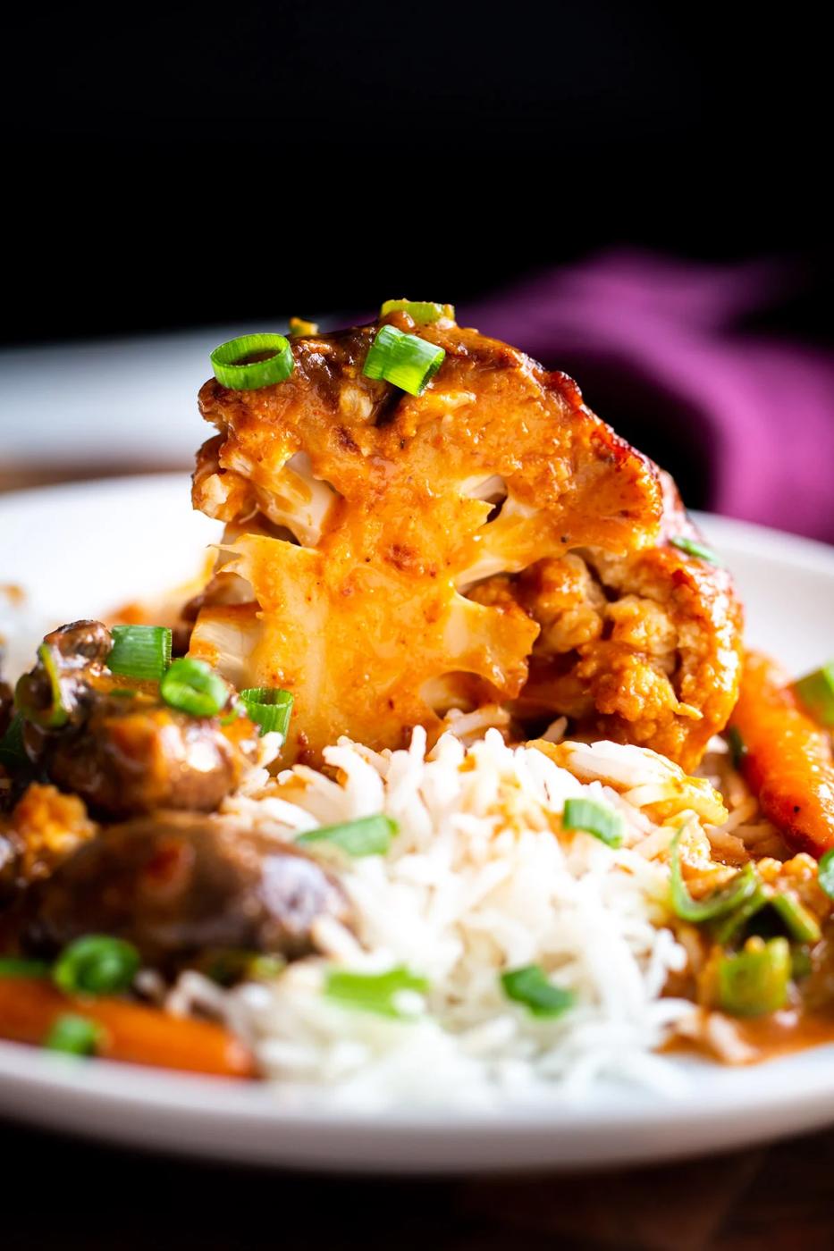 a wedge of a whole glazed peanut butter miso roasted cauliflower served with rice