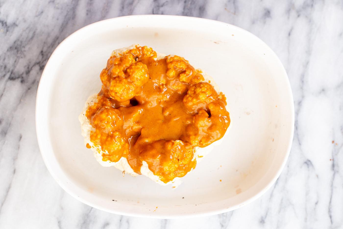vegan whole roasted cauliflower in a white casserole dish