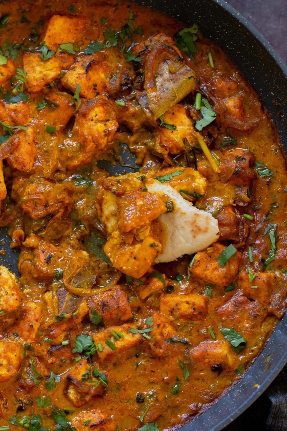 close-up of dipping flatbread into tofu pepper fry in the skillet