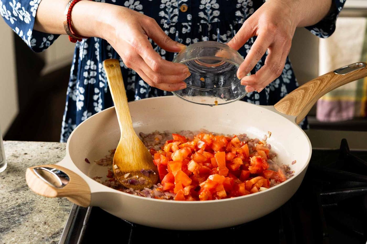 adding tomato to the pan