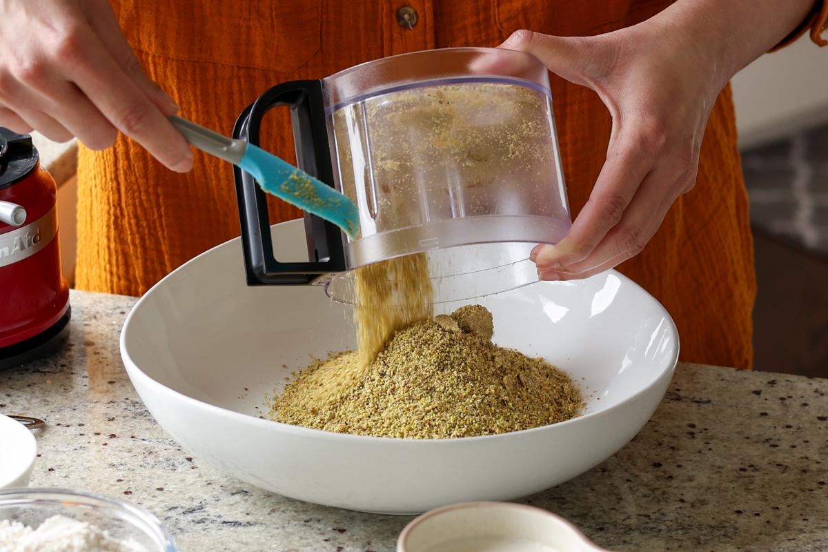 adding ground pistachios to a bowl