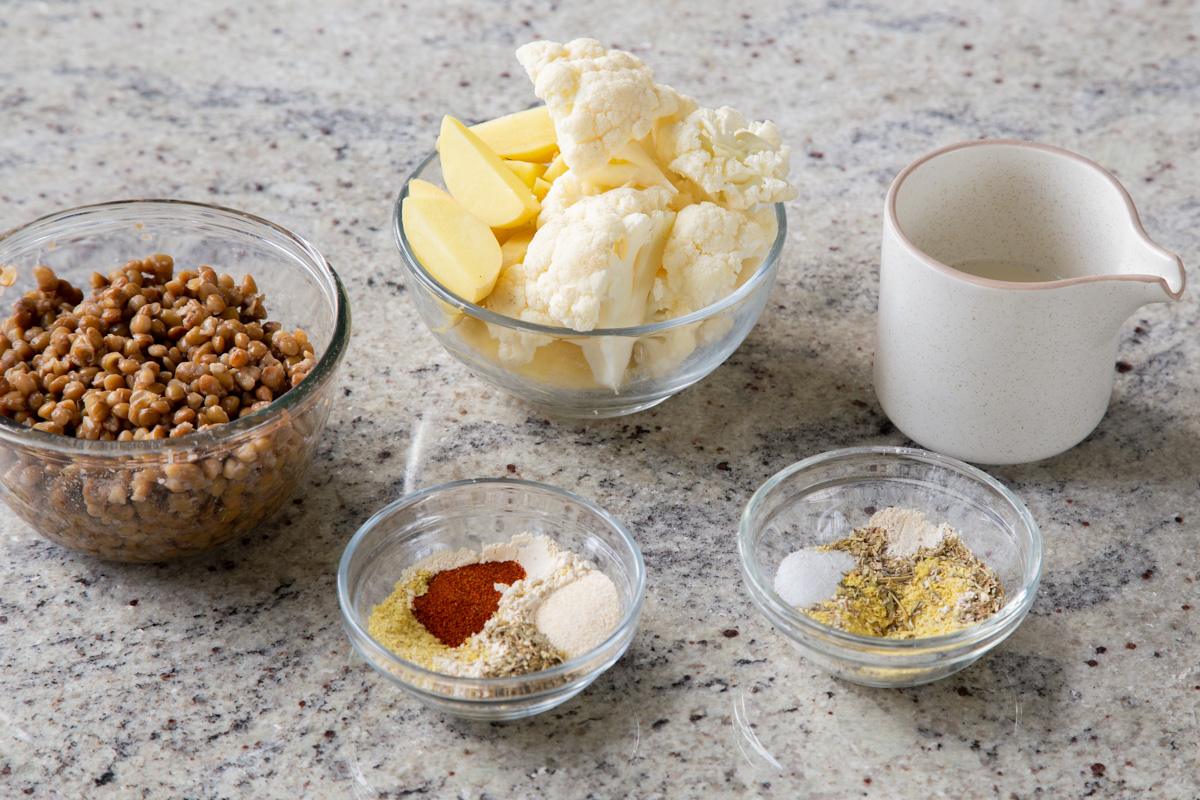 cauliflower, potatoes, lentils, and other mash ingredients in bowls on the kitchen counter