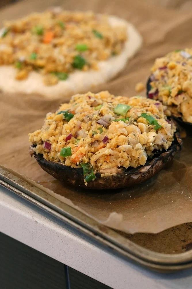 Vegan stuffed Portobello mushrooms with chickpea filling lined up on a baking sheet