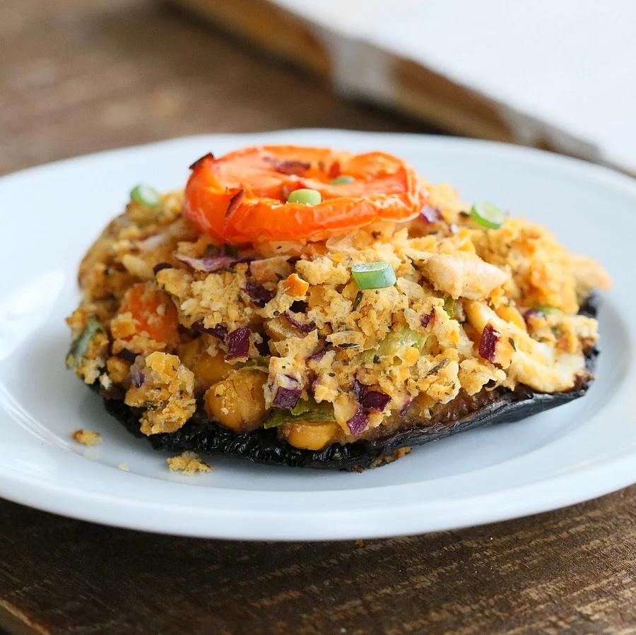 side view of a vegan chickpea stuffed portobello mushroom on a white plate