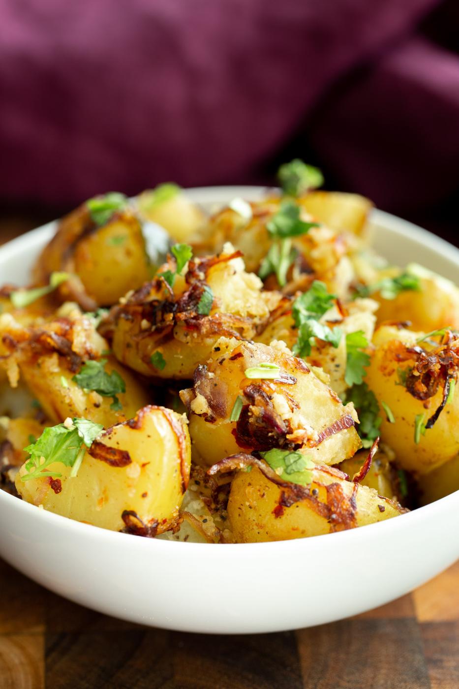 close-up of a bowl of Indian potato pepper stir-fry with mustard seeds and curry leaves