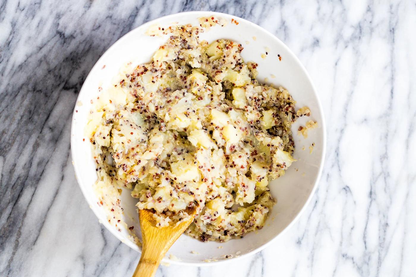 potatoes and quinoa being mashed in a bowl