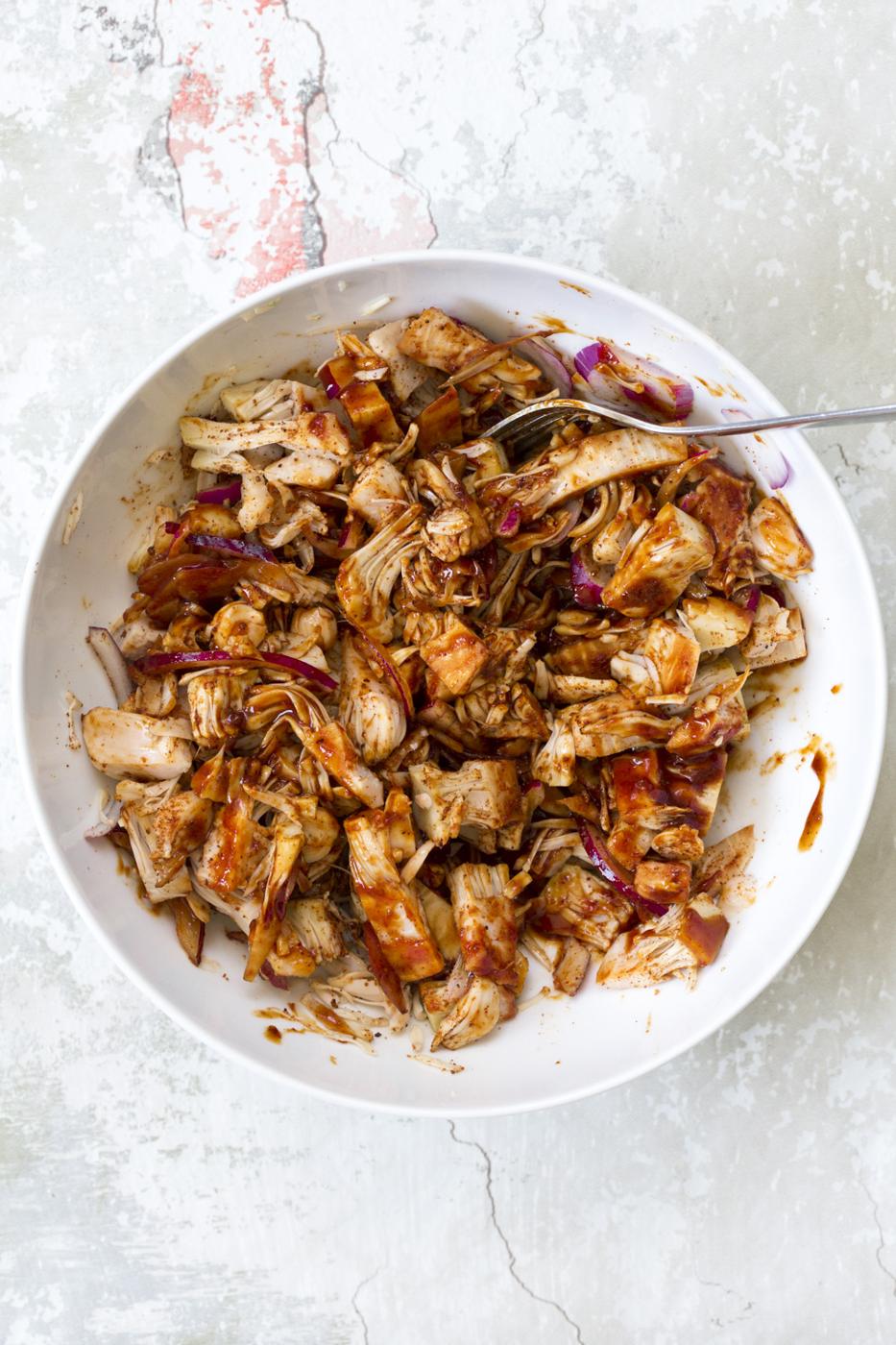 Shredded Jackfruit mixed with bbq sauce and bbq seasoning in a white bowl for our Vegan Pulled Jackfruit Sandwiches
