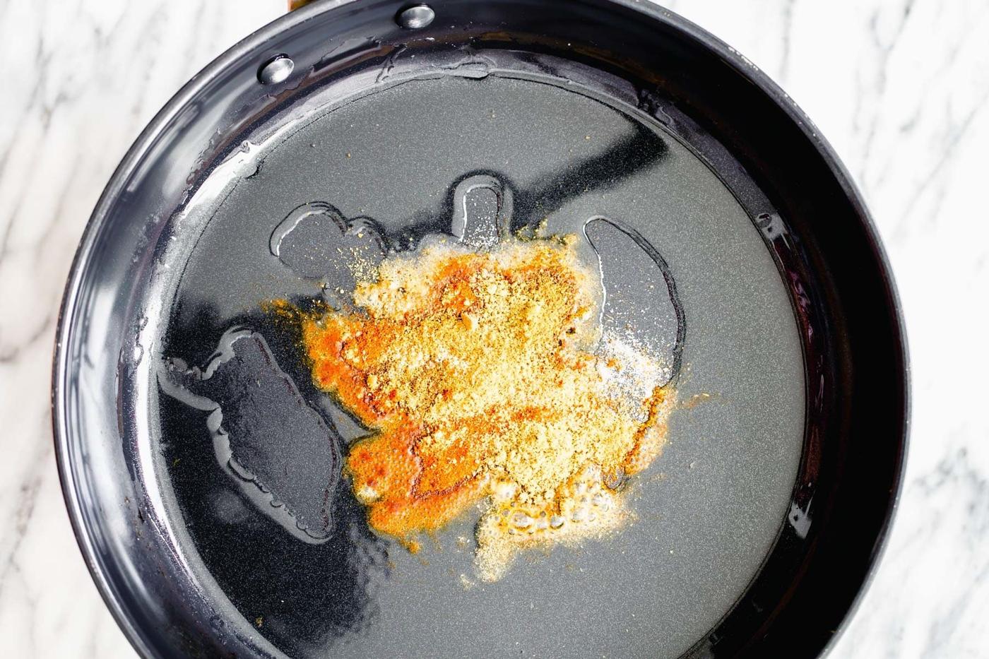 spices being added to hot oil for tempering