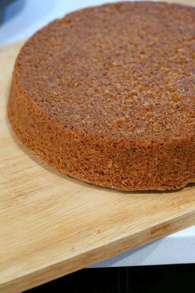 a vegan vanilla sponge cake being transferred to a wooden board