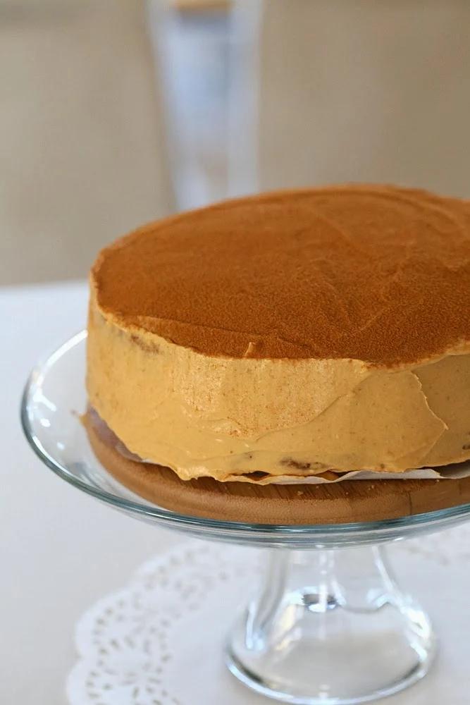side view of a vegan pumpkin mousse cake on a glass cake stand