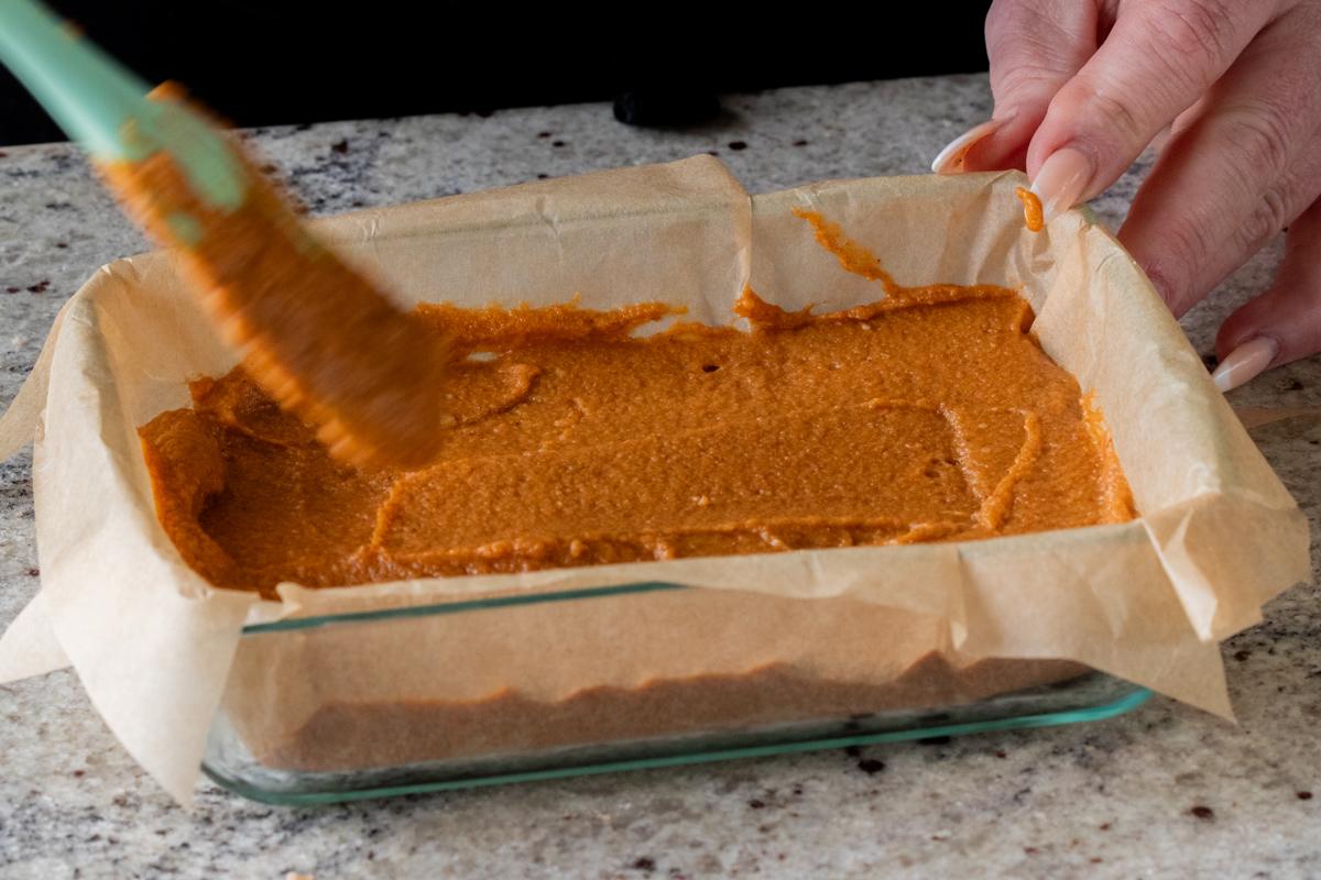 evening out the top of the pumpkin crisp filling in the lined baking pan