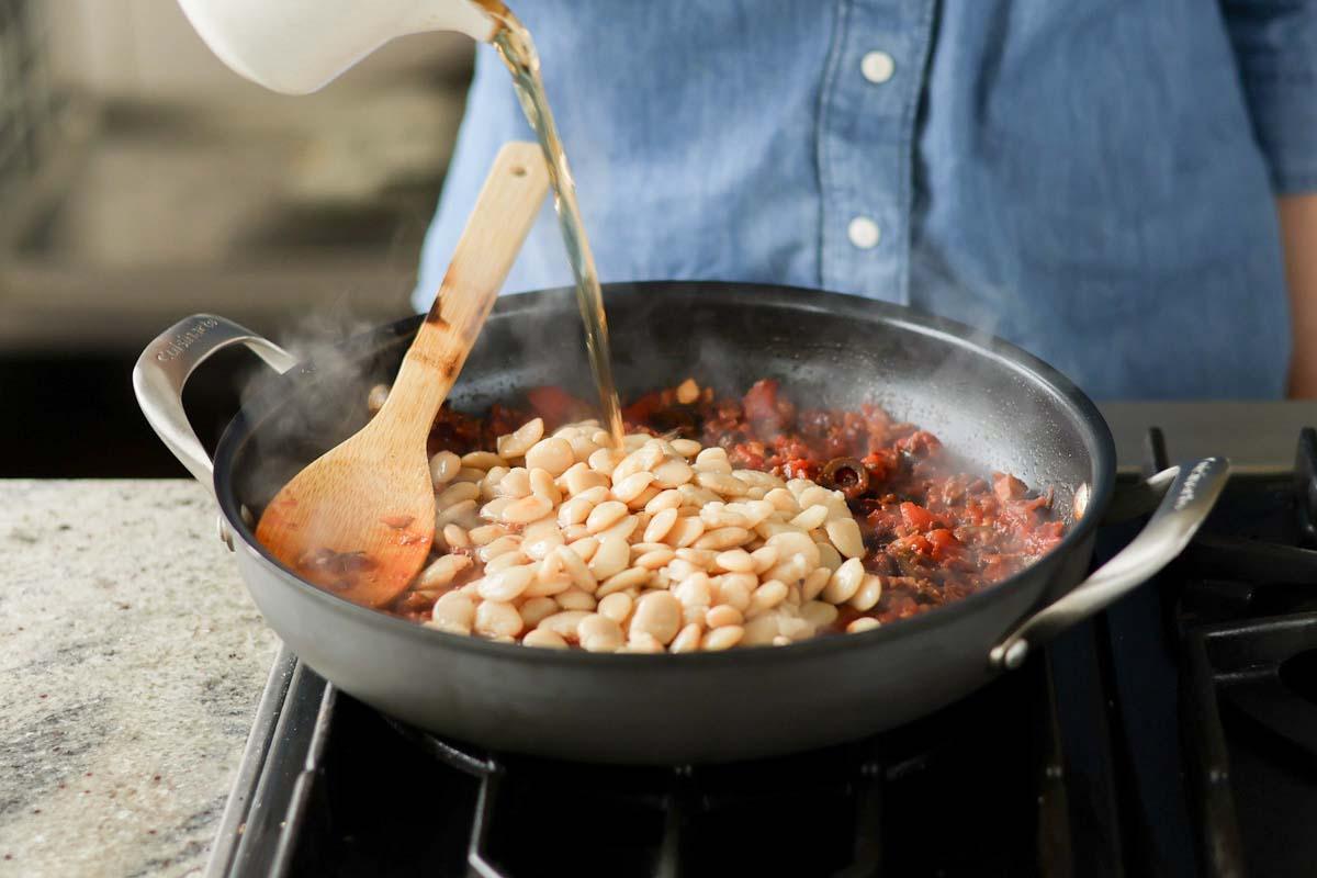 adding butter beans and water to the pan