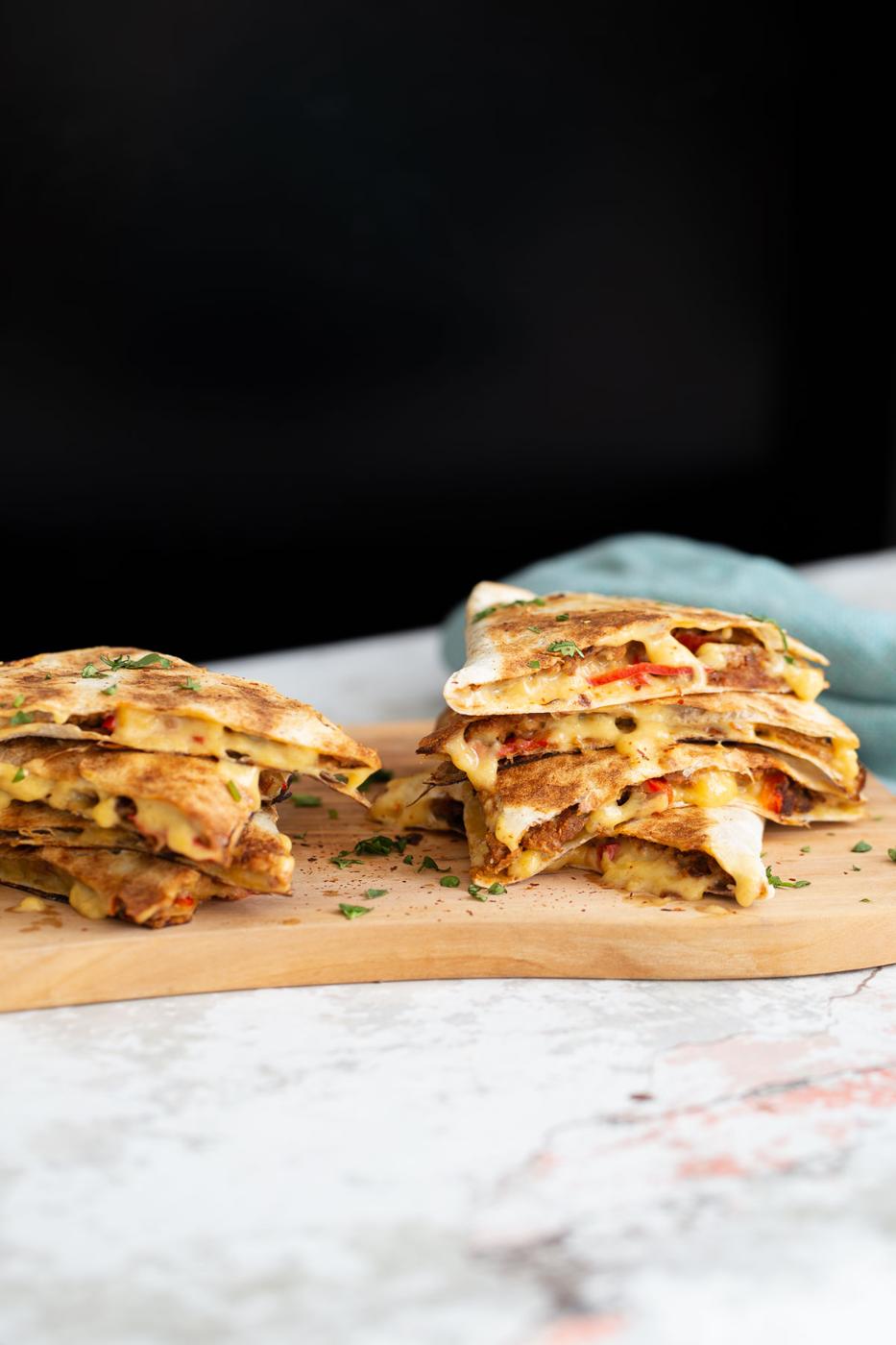 side view of vegan quesadillas filled with vegan walnut taco meat, bell pepper and melted cheese