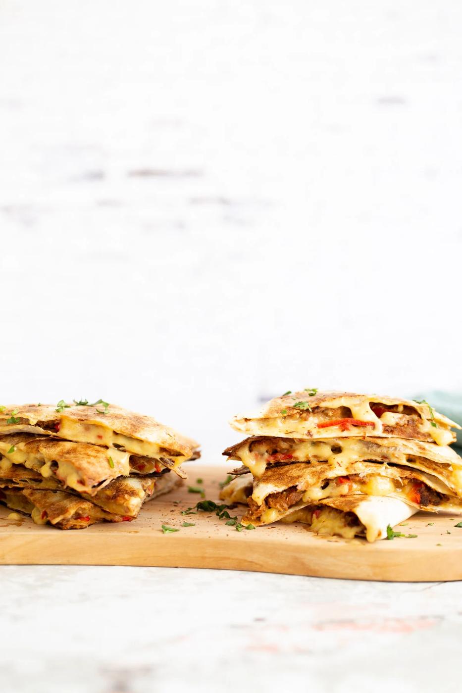 two stacks of quesadillas filled with vegan walnut taco meat on a chopping board