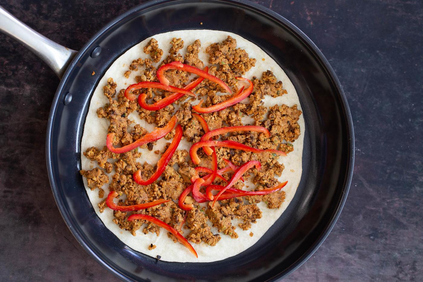 vegan walnut taco meat quesadilla being assembled in black skillet