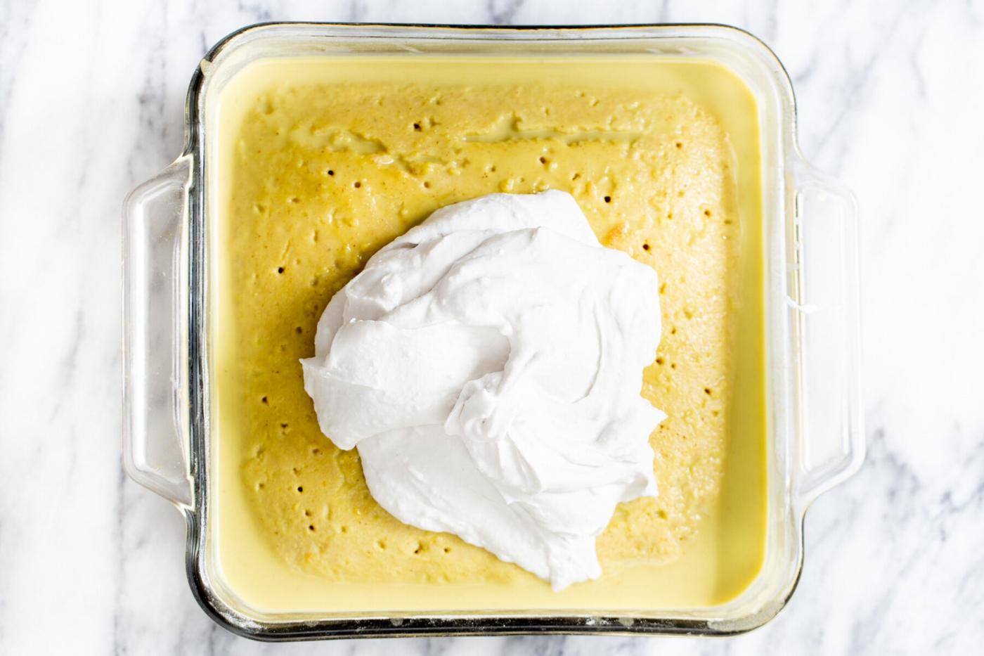 coconut whip being spread over vegan tres leches in a pyrex pan