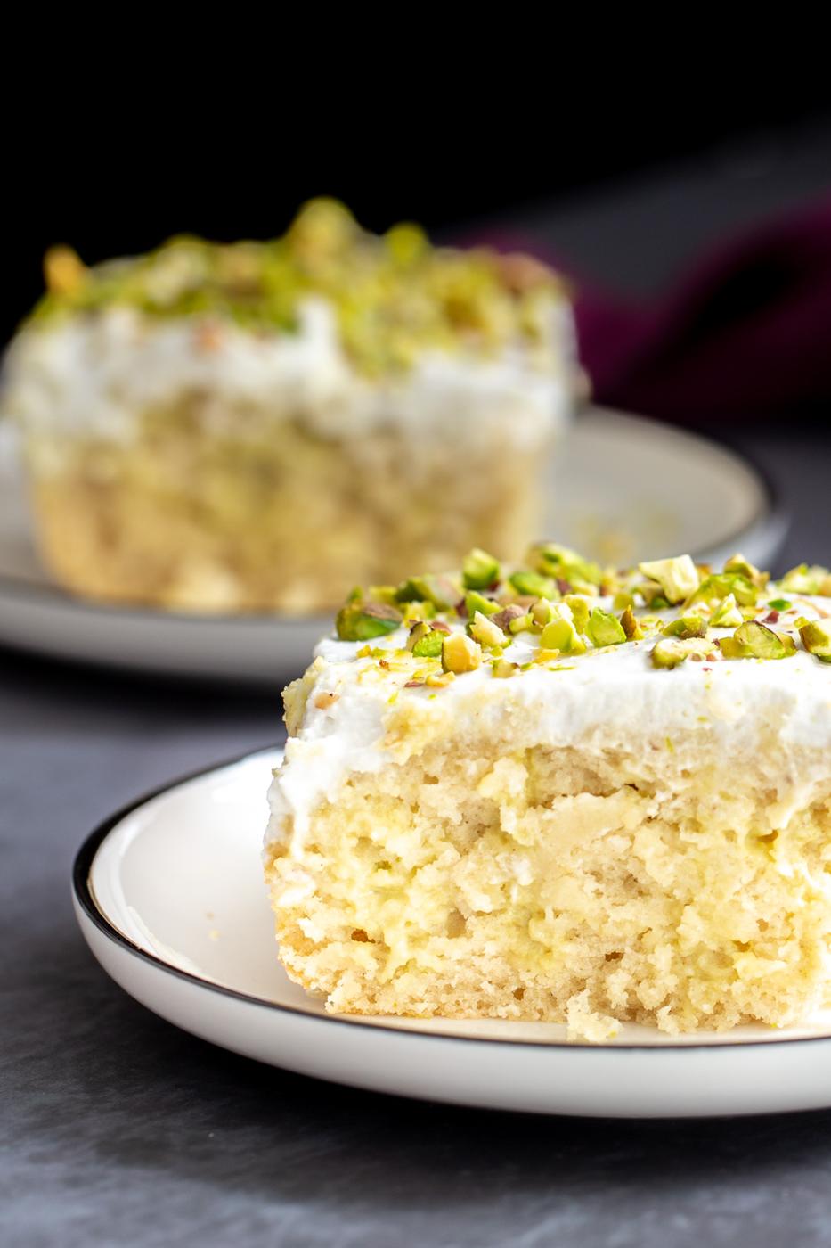 side view of a slice of vegan tres leches cake sprinkled with pistachios