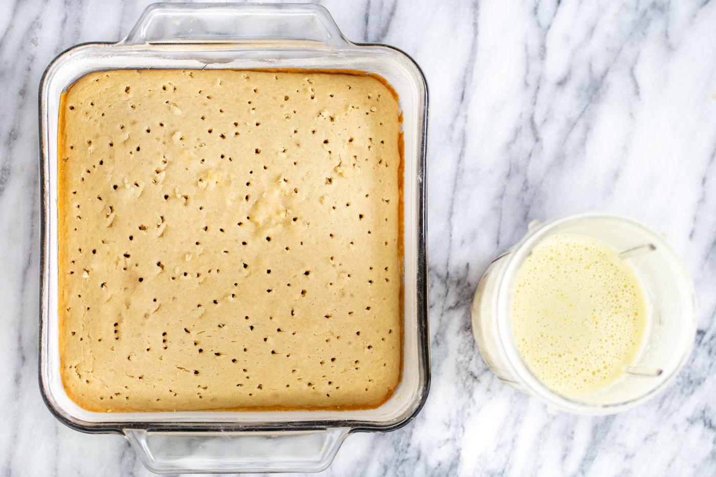 nut milk mix in a blender container next to a baked tres leches sponge