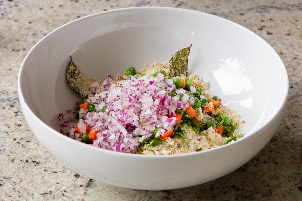 adding veggies to the semolina mixture in the bowl